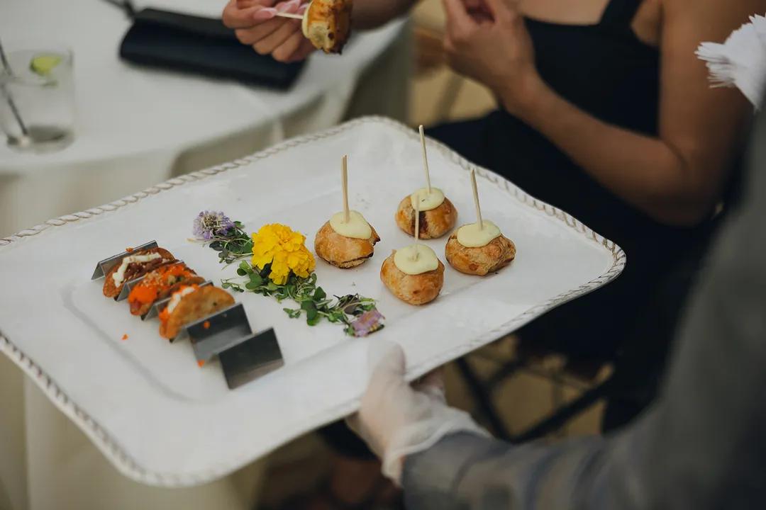 Server presenting a tray of bite-sized appetizers.