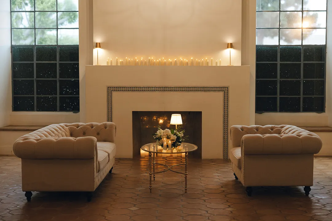 Two tufted sofas facing a candlelit fireplace in the lounge.