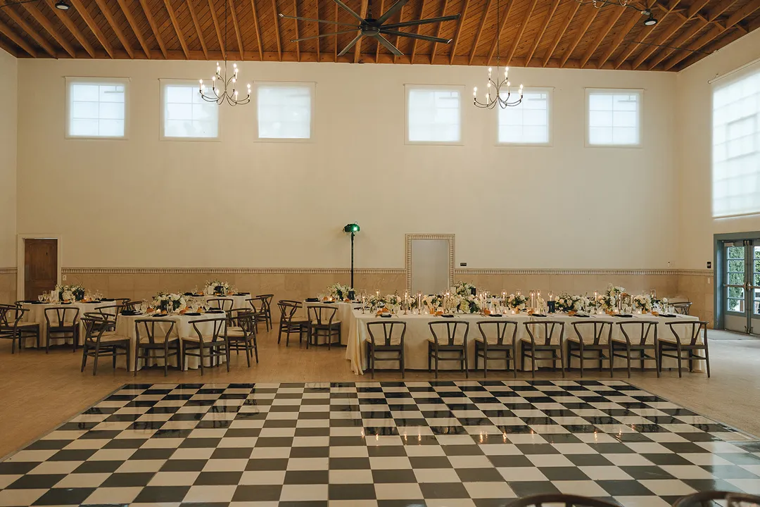 Black-and-white checkered dance floor beside reception tables.