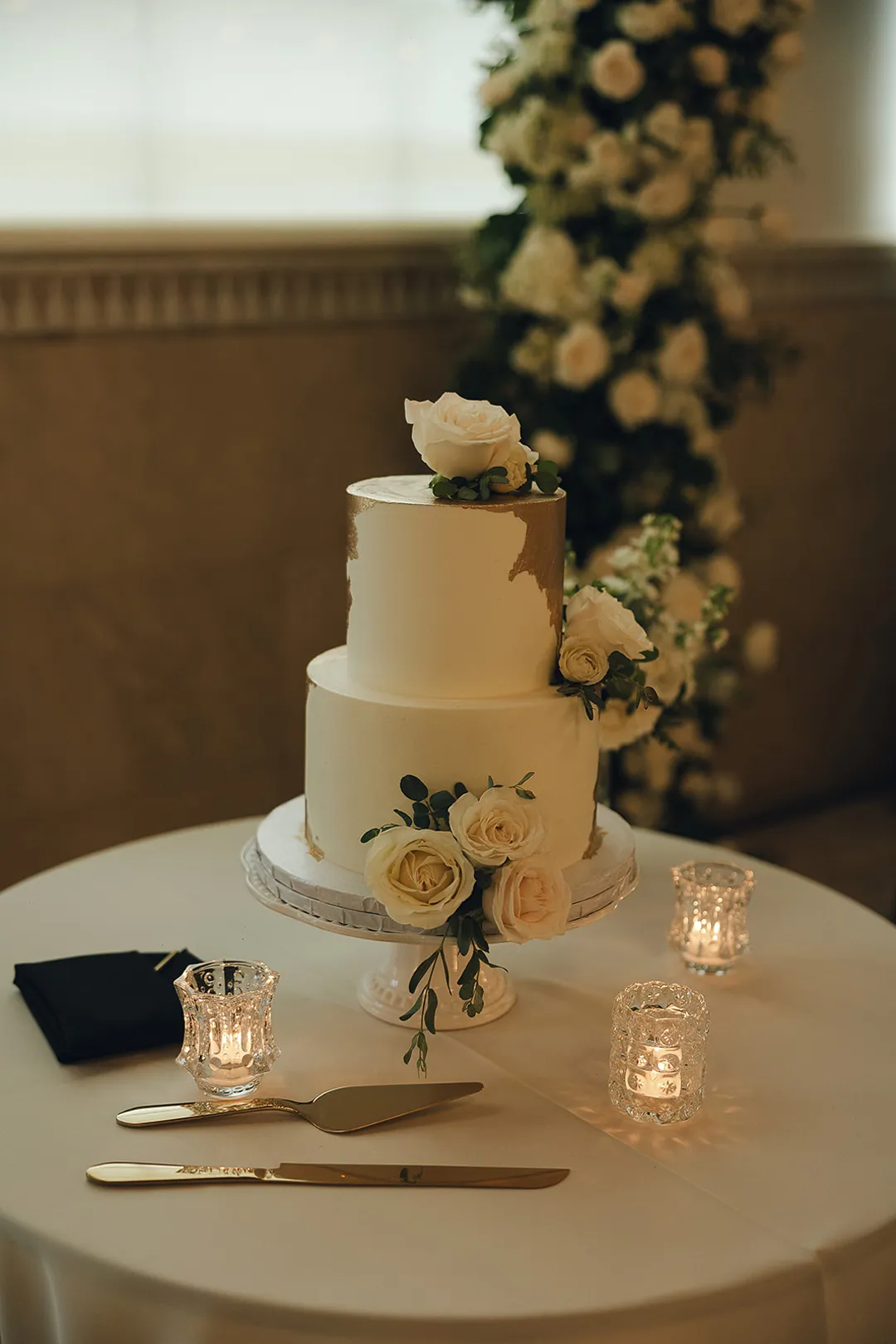 Three-tier white wedding cake decorated with pale roses.