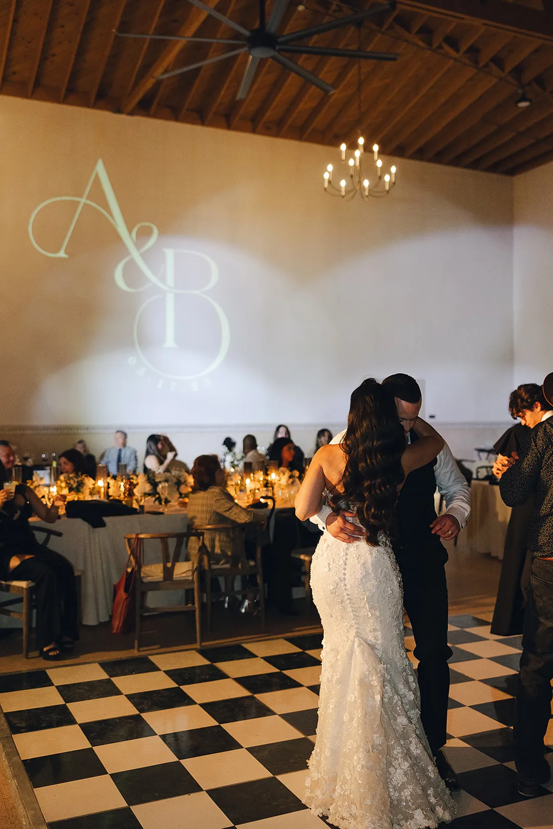 Wedding couple embracing on the dance floor beneath a projected monogram.