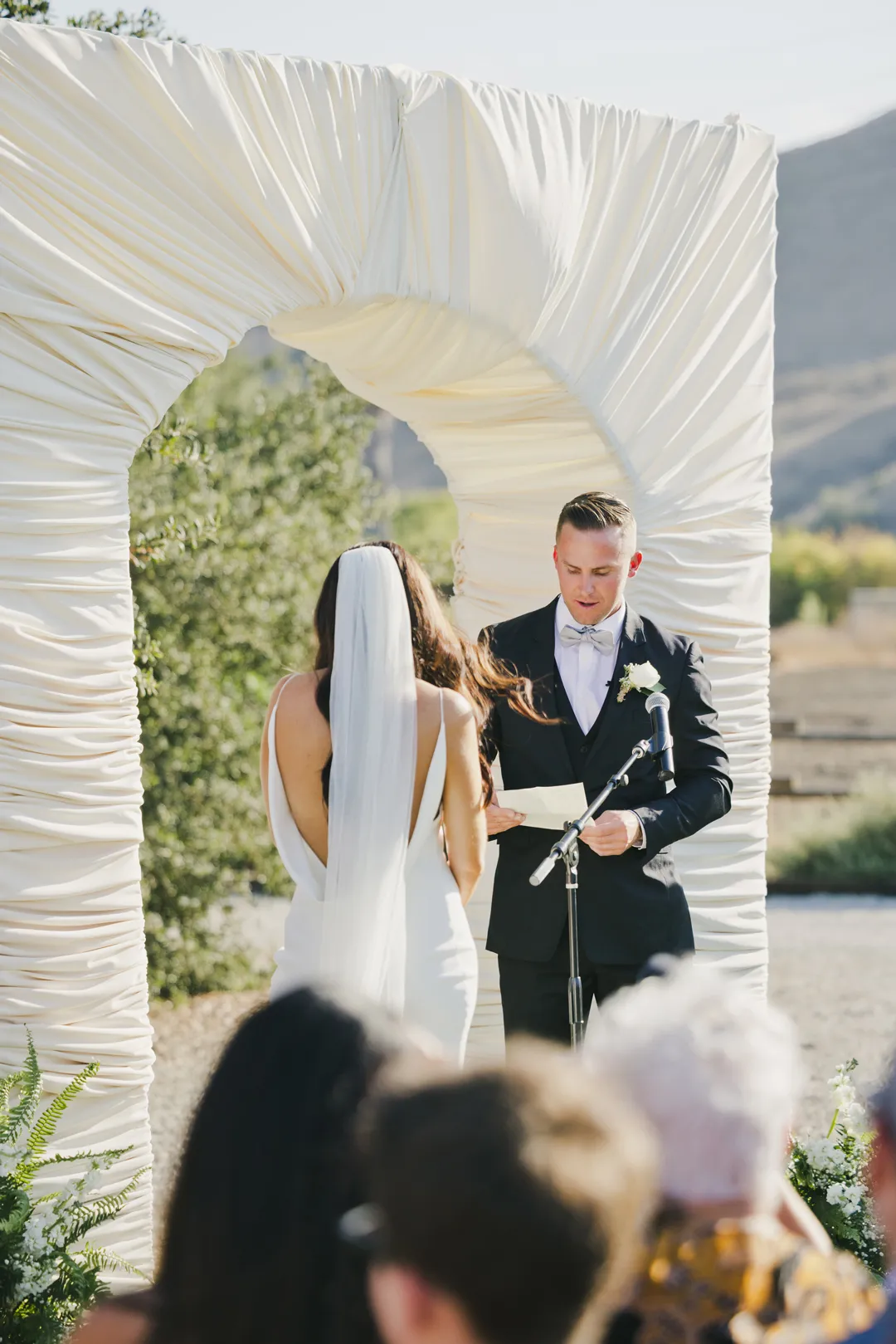 Groom reading his vows to the bride outdoors.