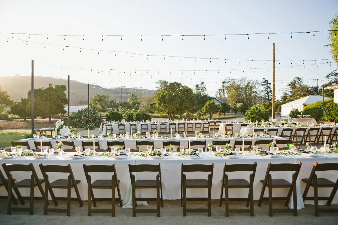 Outdoor reception tables beneath strings of lights.