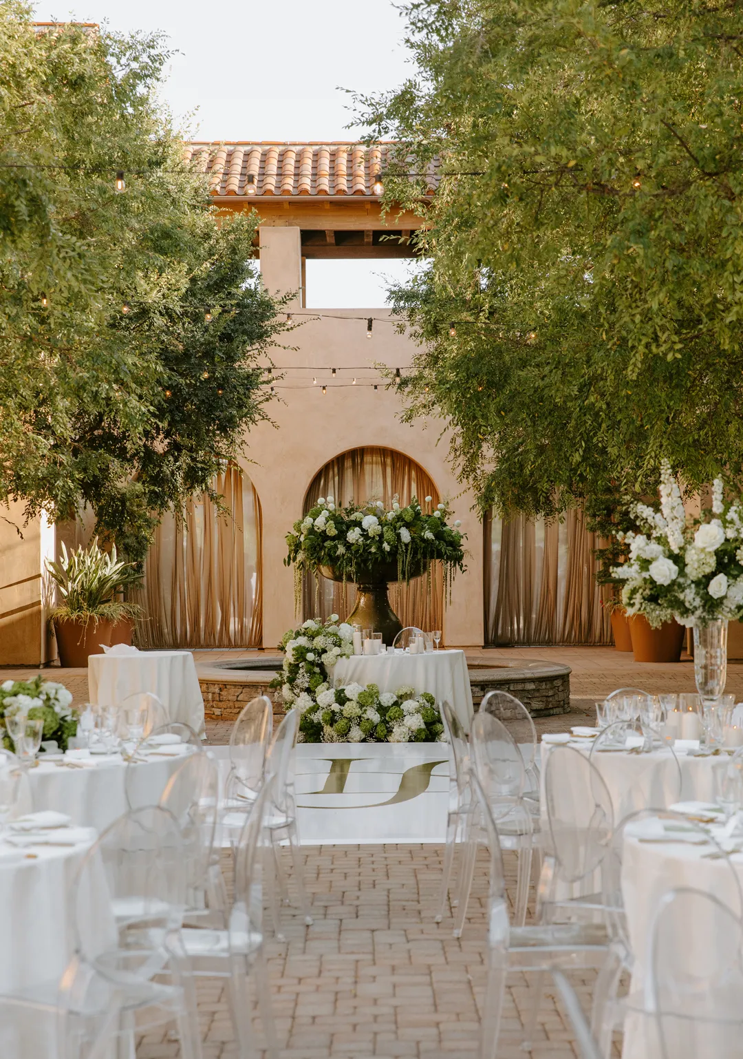 Courtyard reception tables arranged around a flower-decorated fountain.