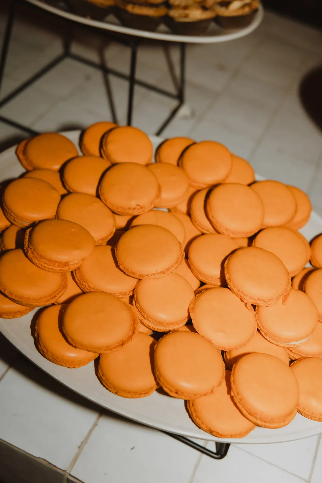Orange macarons piled on a dessert platter.