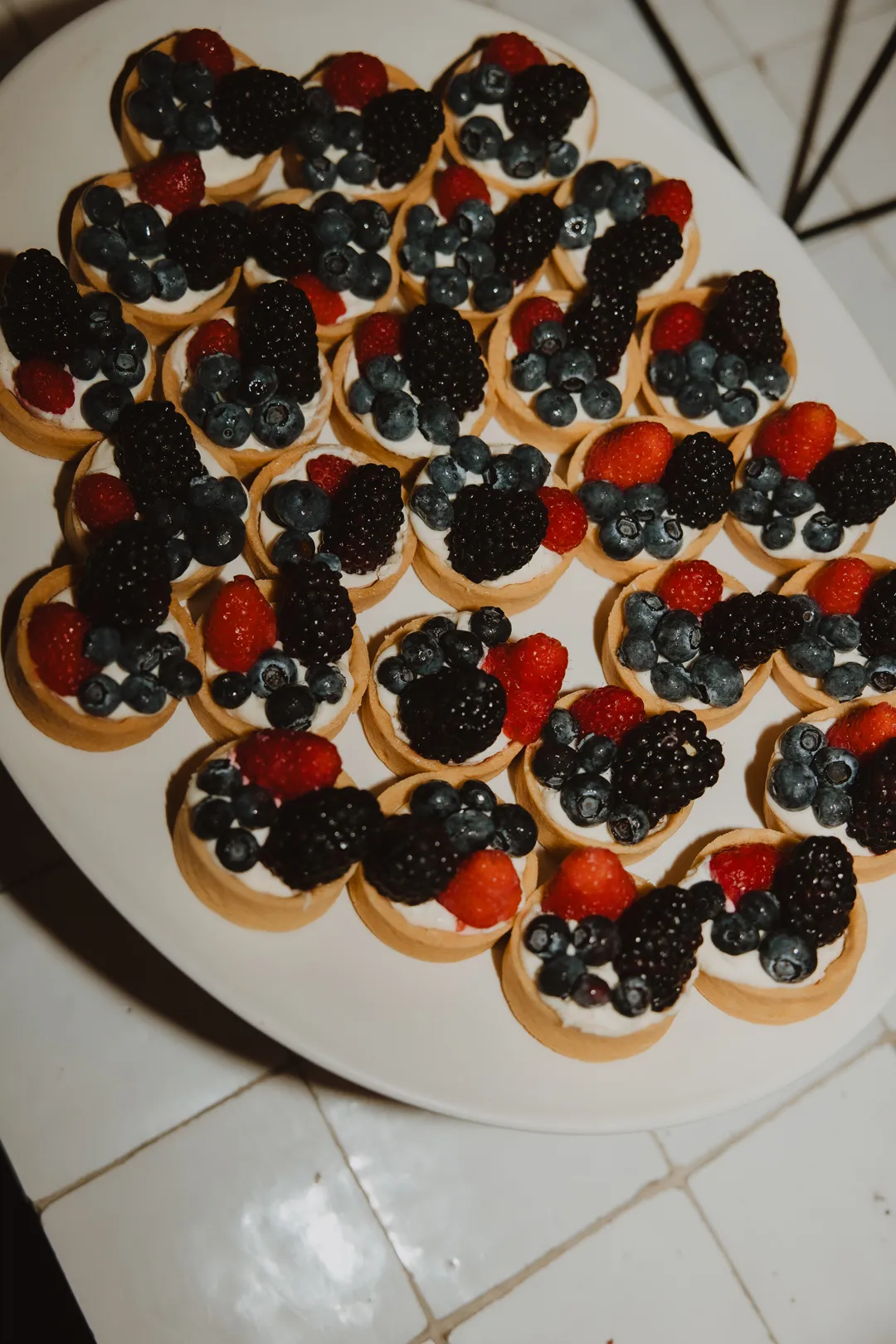 Miniature fruit tarts topped with assorted berries.