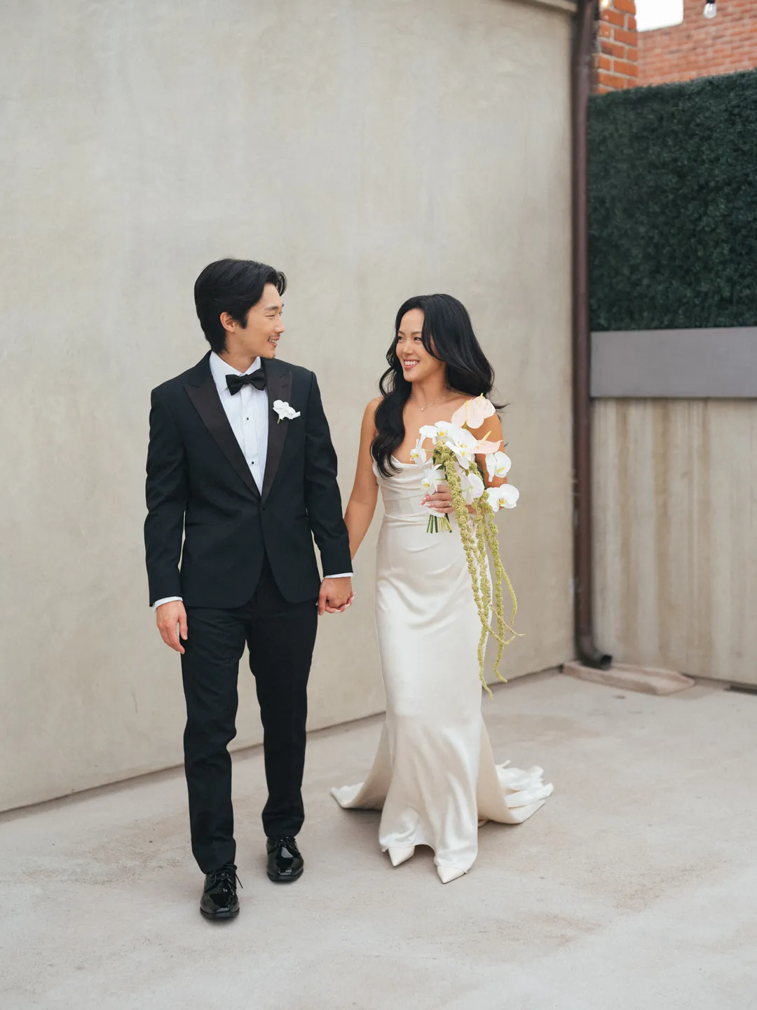 Wedding couple holding hands outside the brick venue.