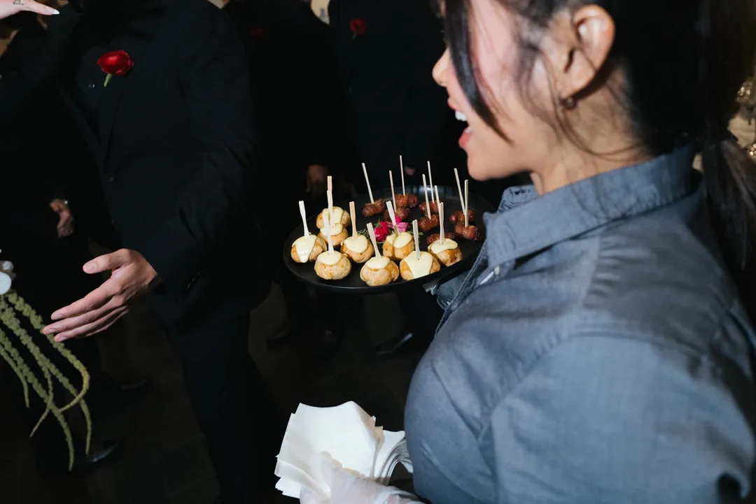 Server offering bite-sized appetizers to wedding guests.