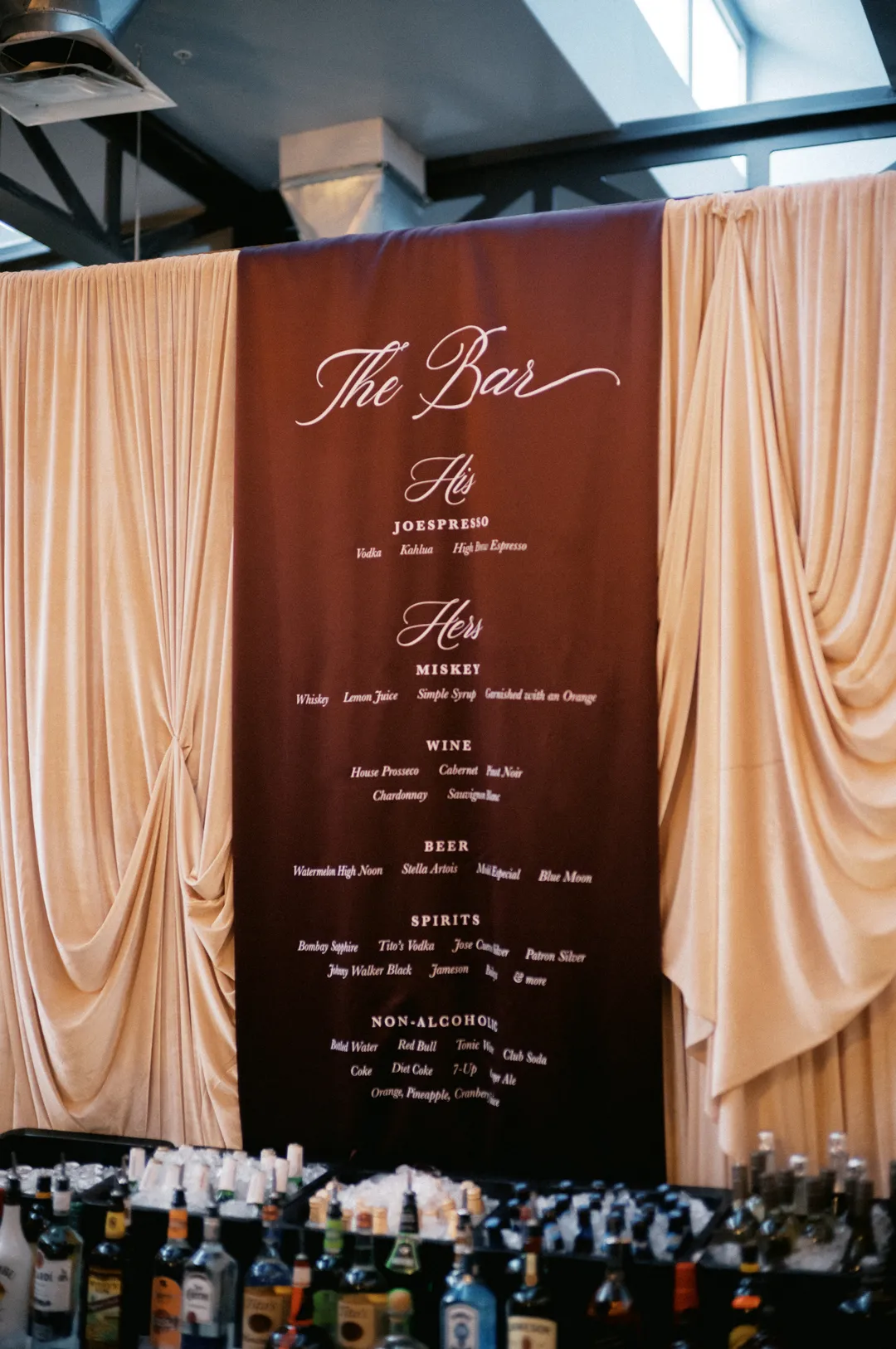 Long burgundy bar menu between gathered fabric panels.