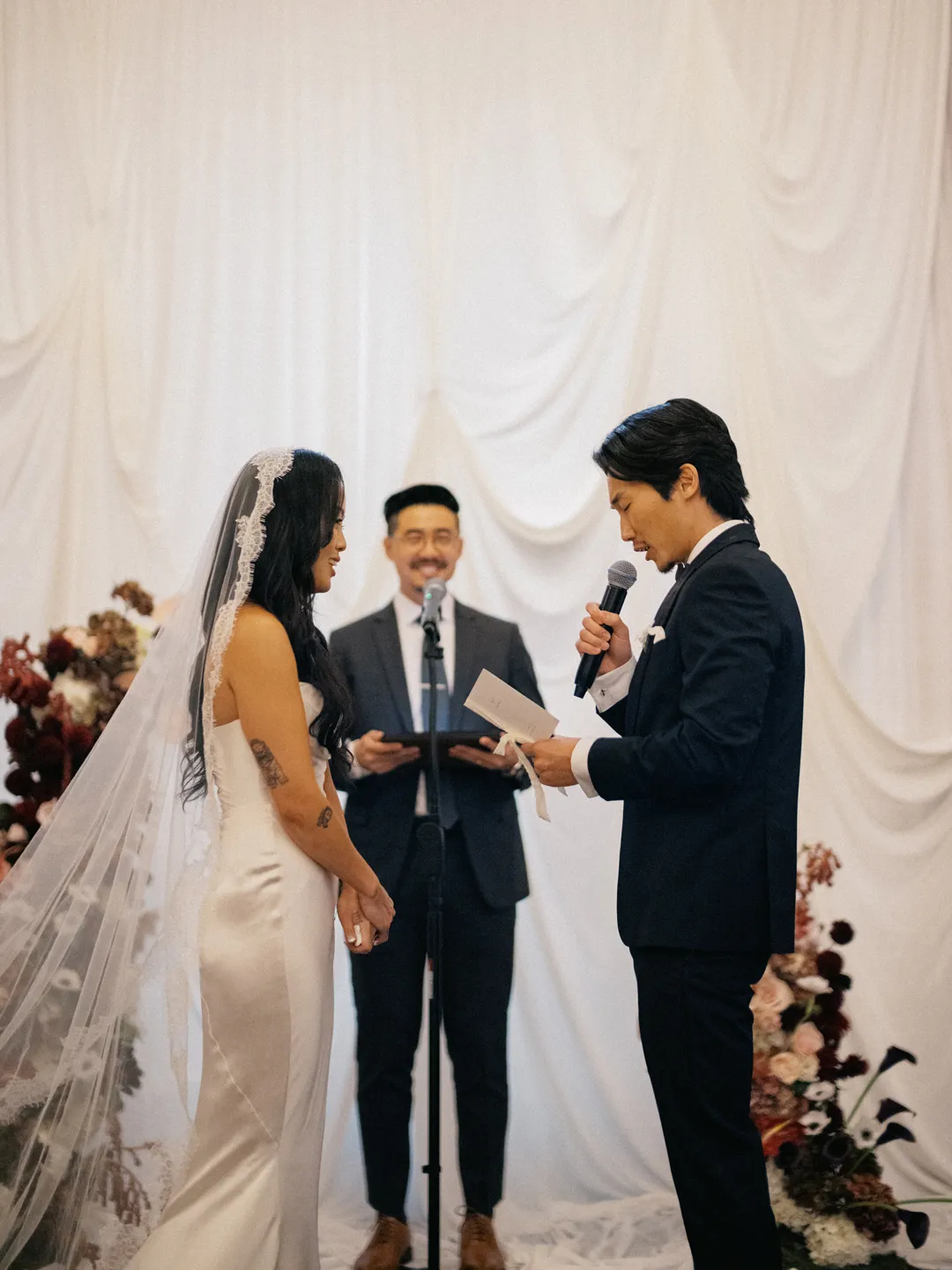Groom reading his vows into a microphone.
