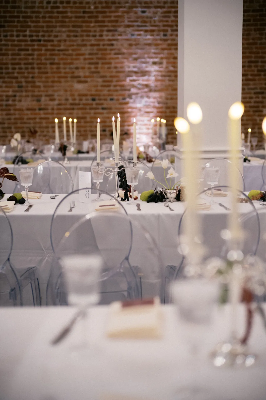 Reception place settings with taper candles and small floral arrangements.