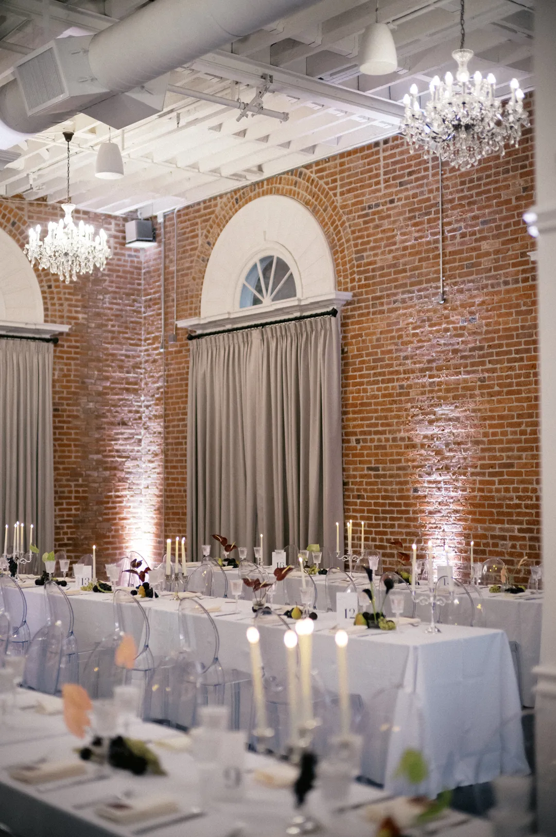 Reception tables beside tall curtained arched windows.