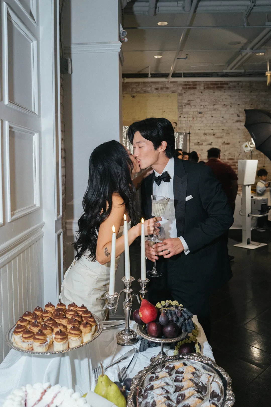 Wedding couple kissing beside the dessert display.