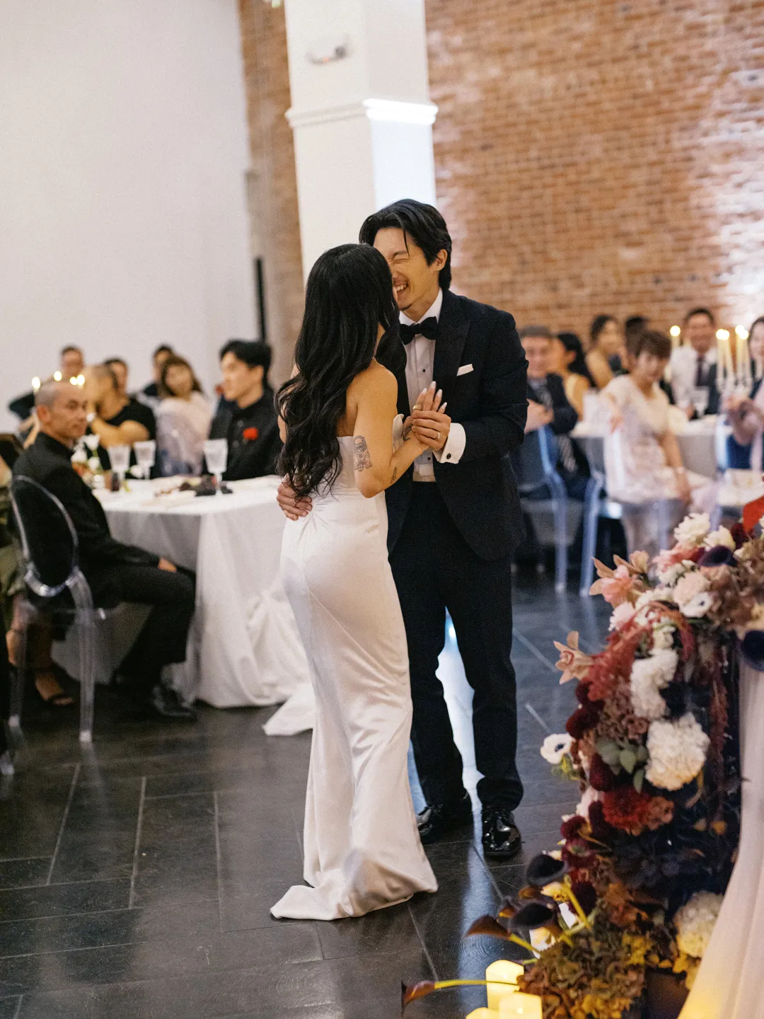 Wedding couple sharing their first dance beside the reception tables.