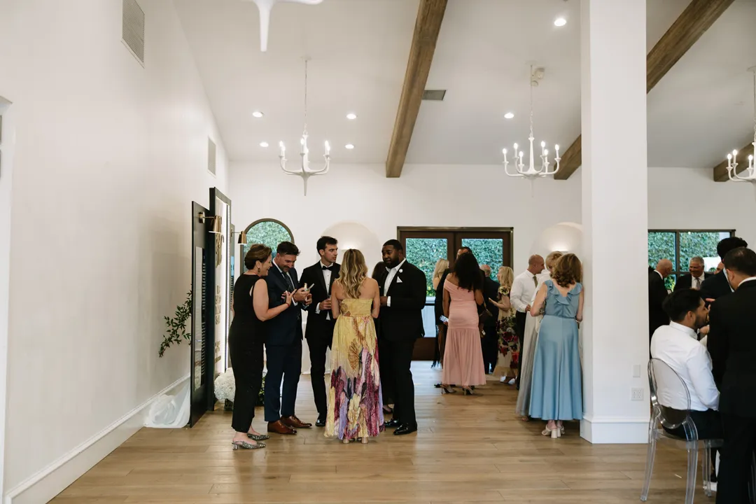 Wedding guests mingling in a bright reception lounge.