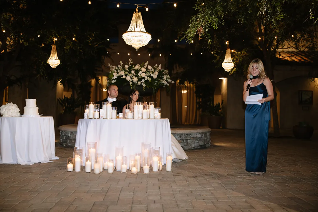 Guest giving a toast beside the couple's candlelit table.