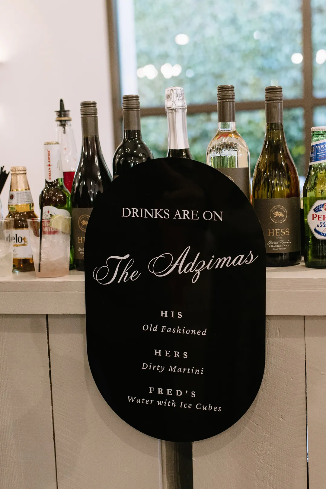 Black oval bar menu displayed in front of wine bottles.