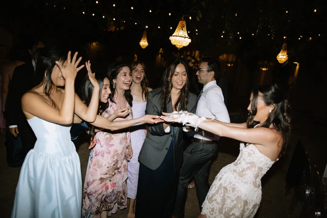 Bride holding out her gloved hands as guests gather around.
