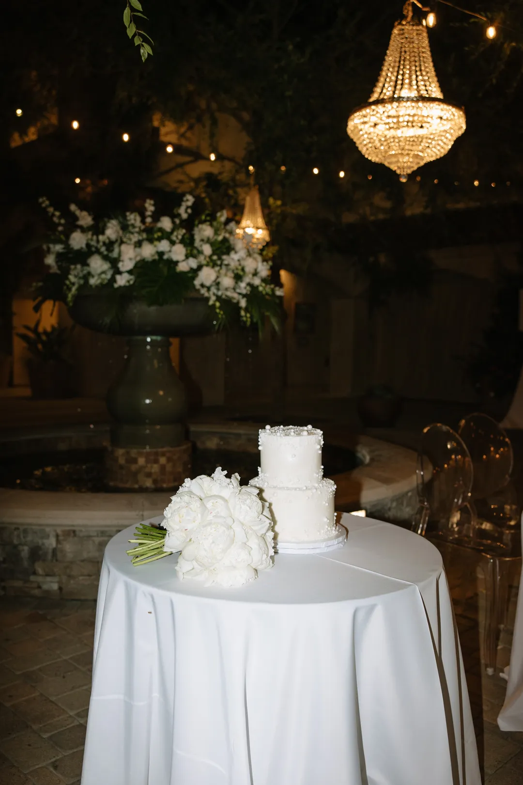 Two-tier white wedding cake beside a white bouquet.
