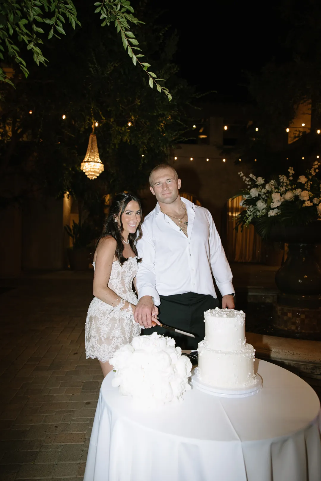 Wedding couple cutting their cake in the courtyard at night.