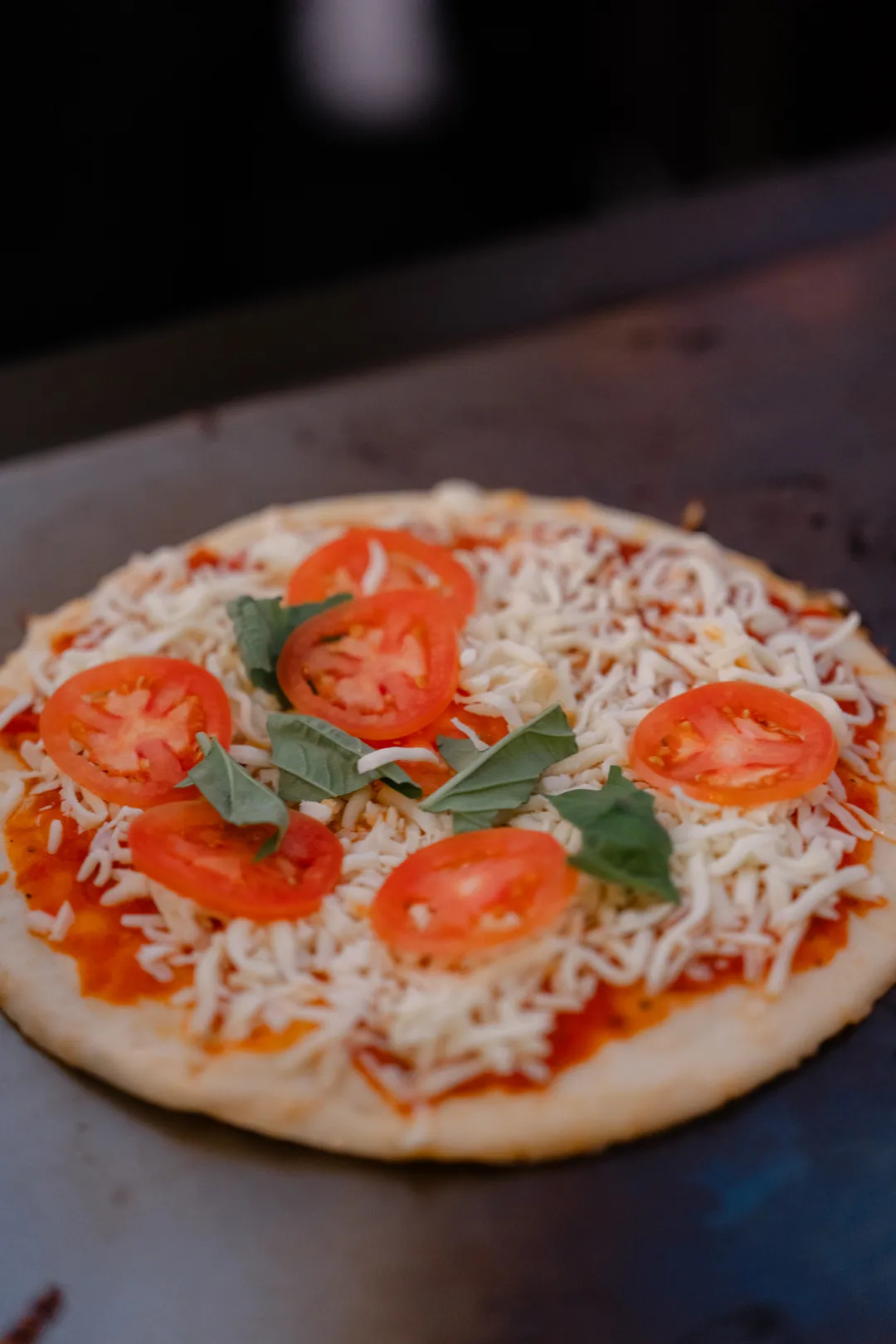 Unbaked pizza topped with tomatoes, basil and cheese.