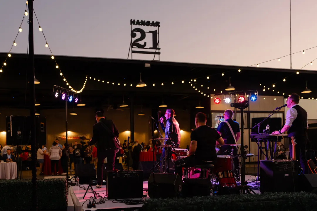Live band performing outside Hangar 21 South at dusk.