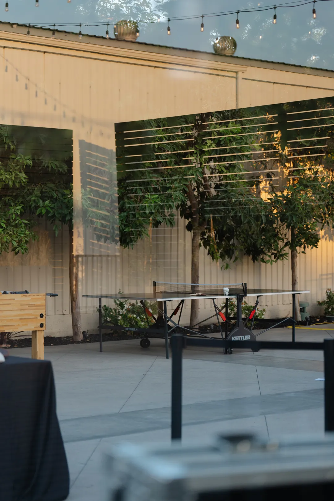 High cocktail table beside a planted courtyard wall.