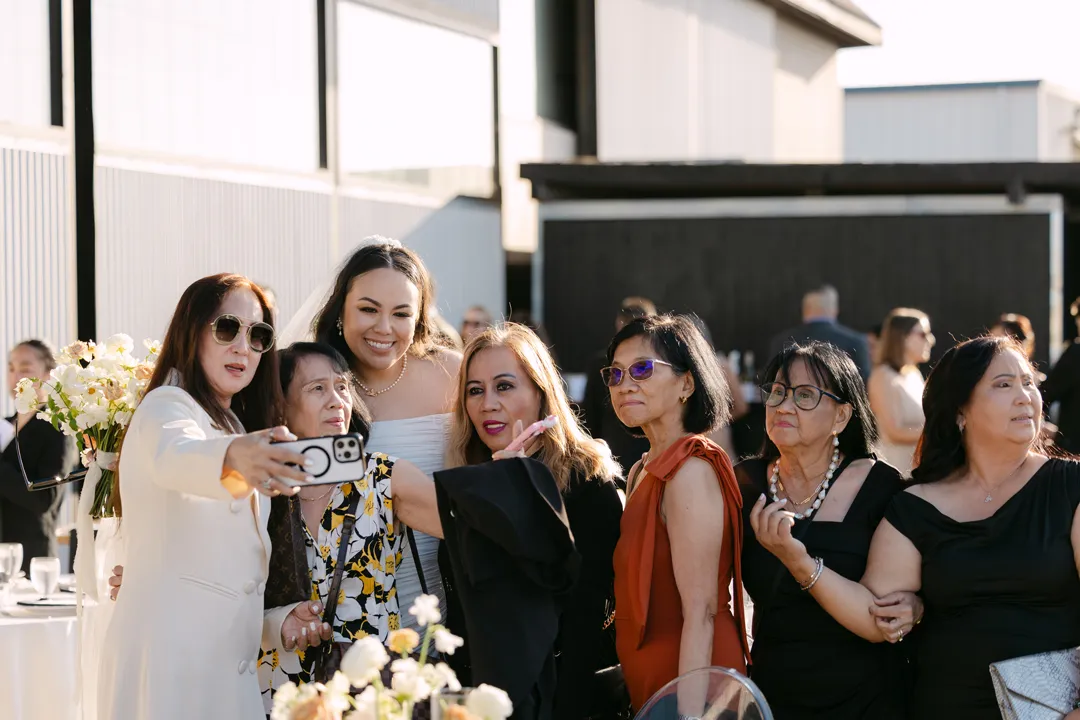 Bride posing for a group selfie with wedding guests.