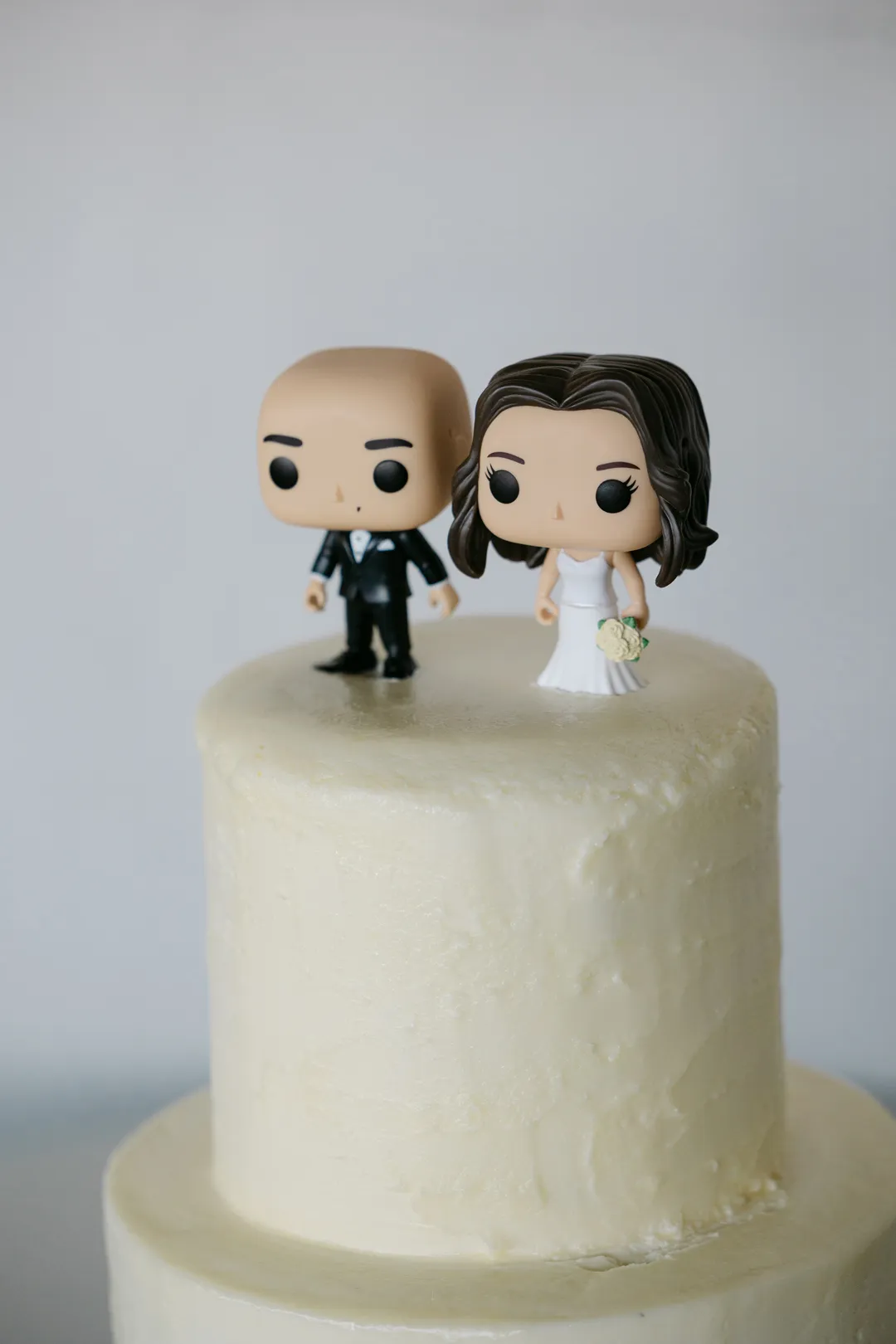 White wedding cake topped with two stylized couple figurines.