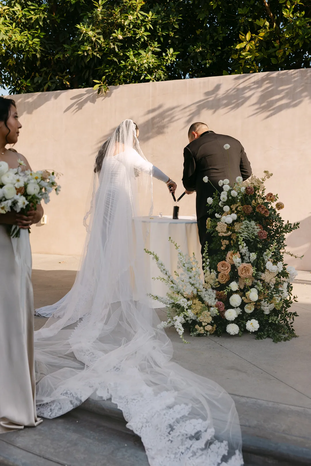 Couple standing at a small ceremony table surrounded by pale flowers.