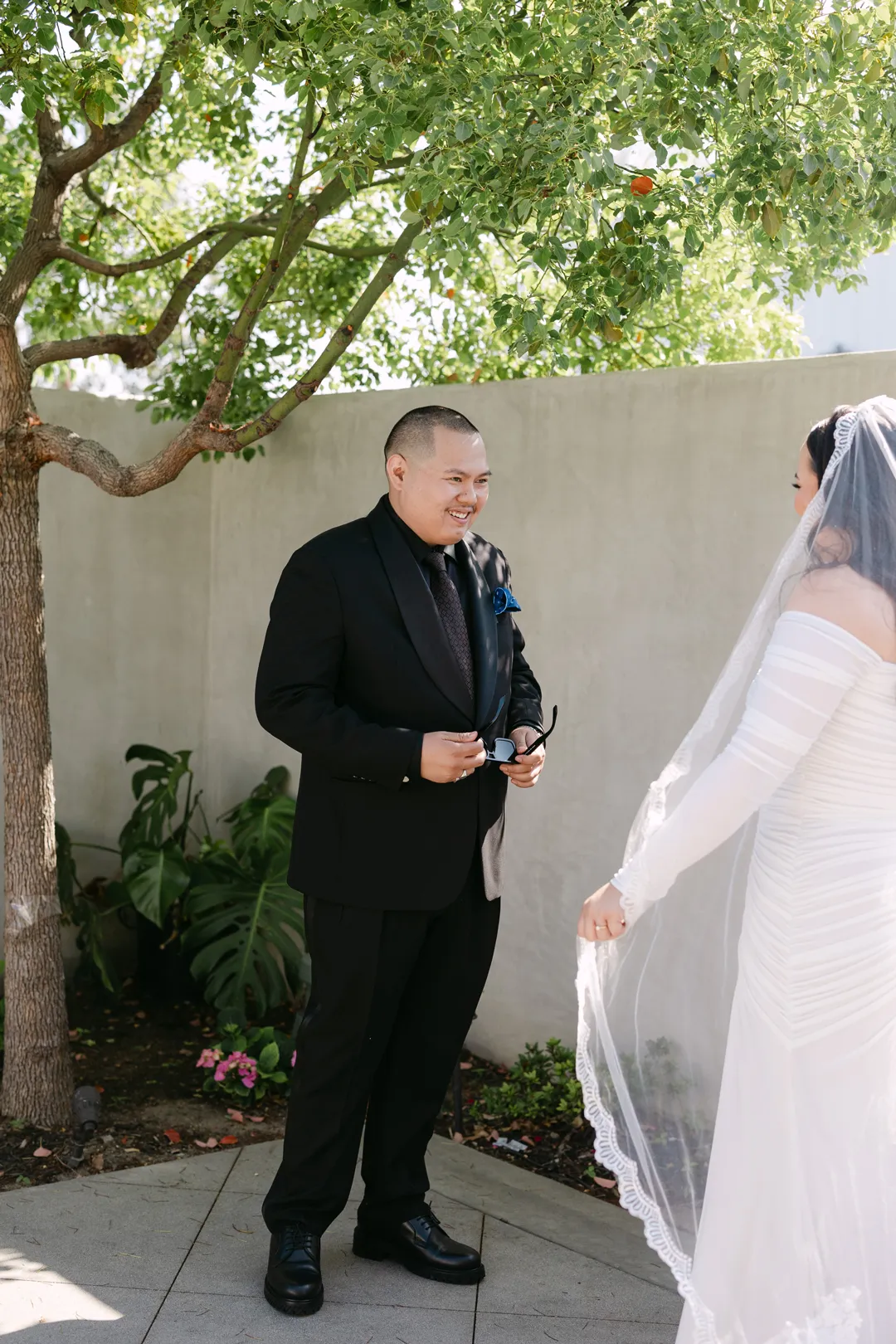 Groom smiling toward the bride during their first look.