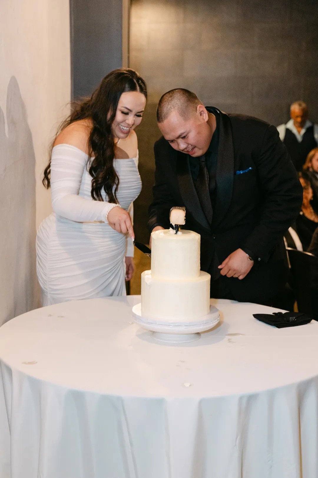 Wedding couple cutting their two-tier white cake.