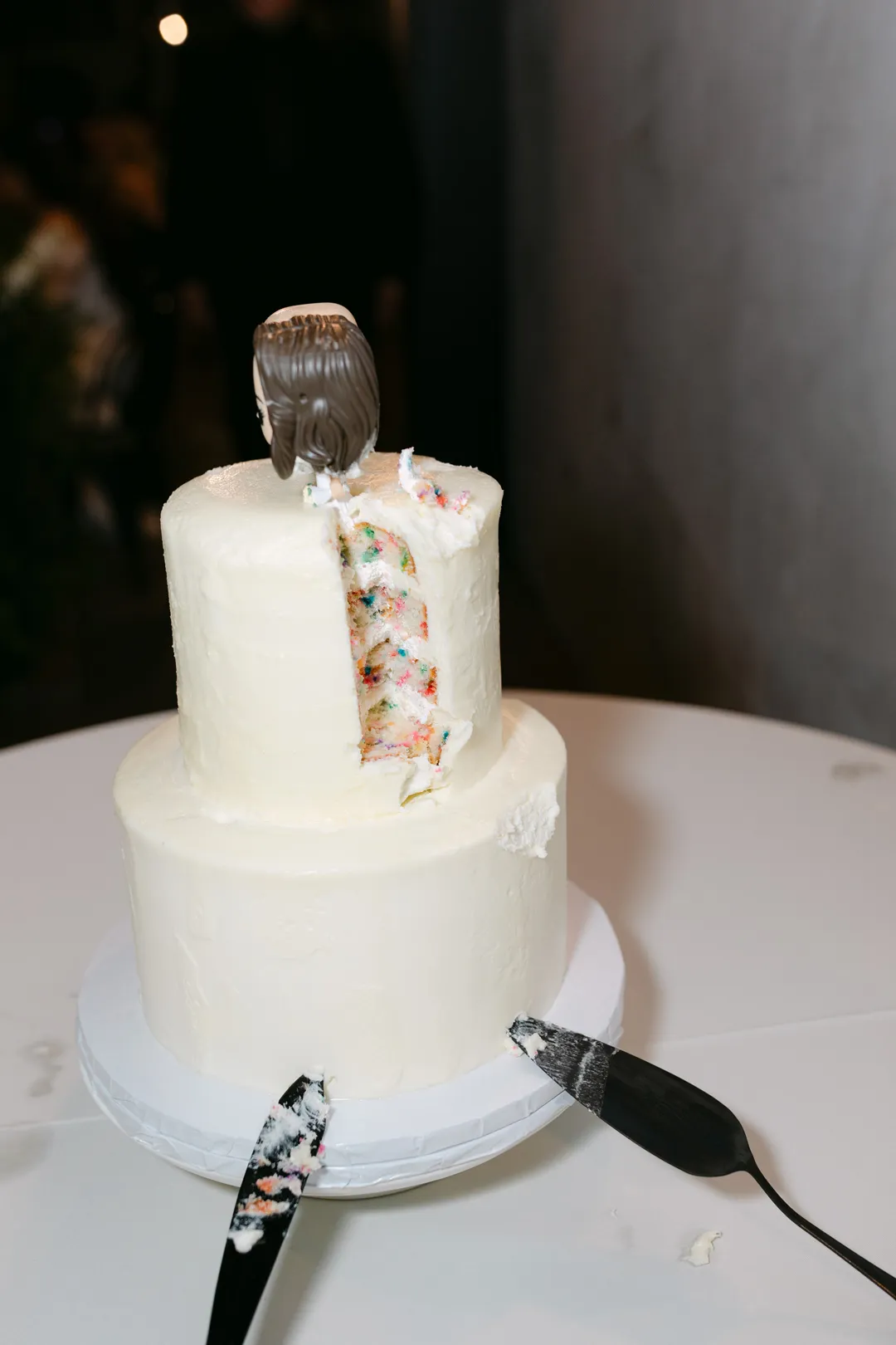 Partially cut wedding cake revealing a colorful sprinkle-filled interior.