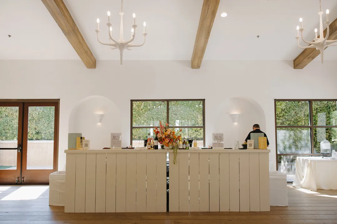 White bar beneath exposed wooden beams in a bright room.