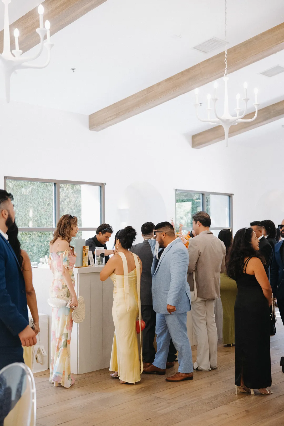 Guests gathered around the bar beneath white chandeliers.