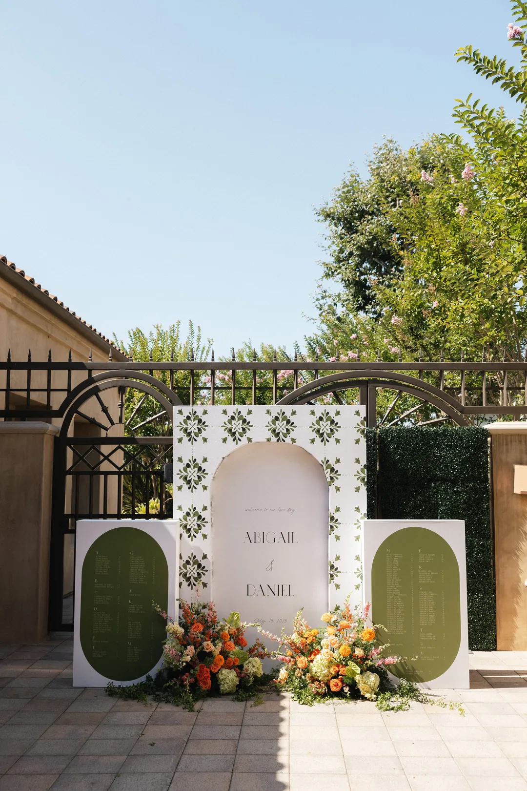 Green and white wedding display with flowers beside a courtyard gate.