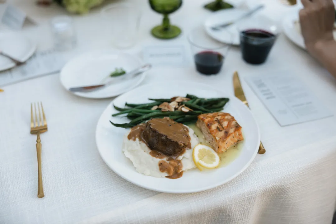 Plated dinner with meat, fish, mashed potatoes and green beans.
