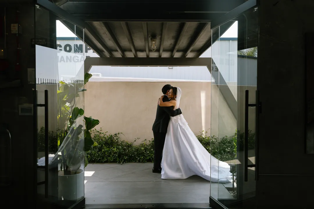 Wedding couple embracing outside the open Hangar 21 South doors.