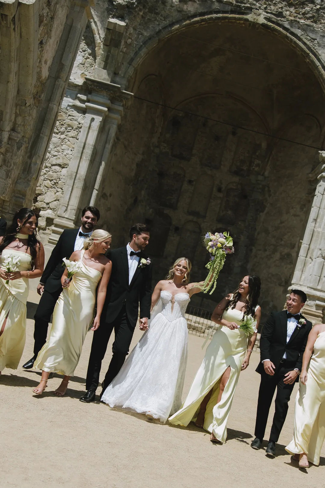 Wedding party celebrating in front of the ruins at Mission San Juan Capistrano.