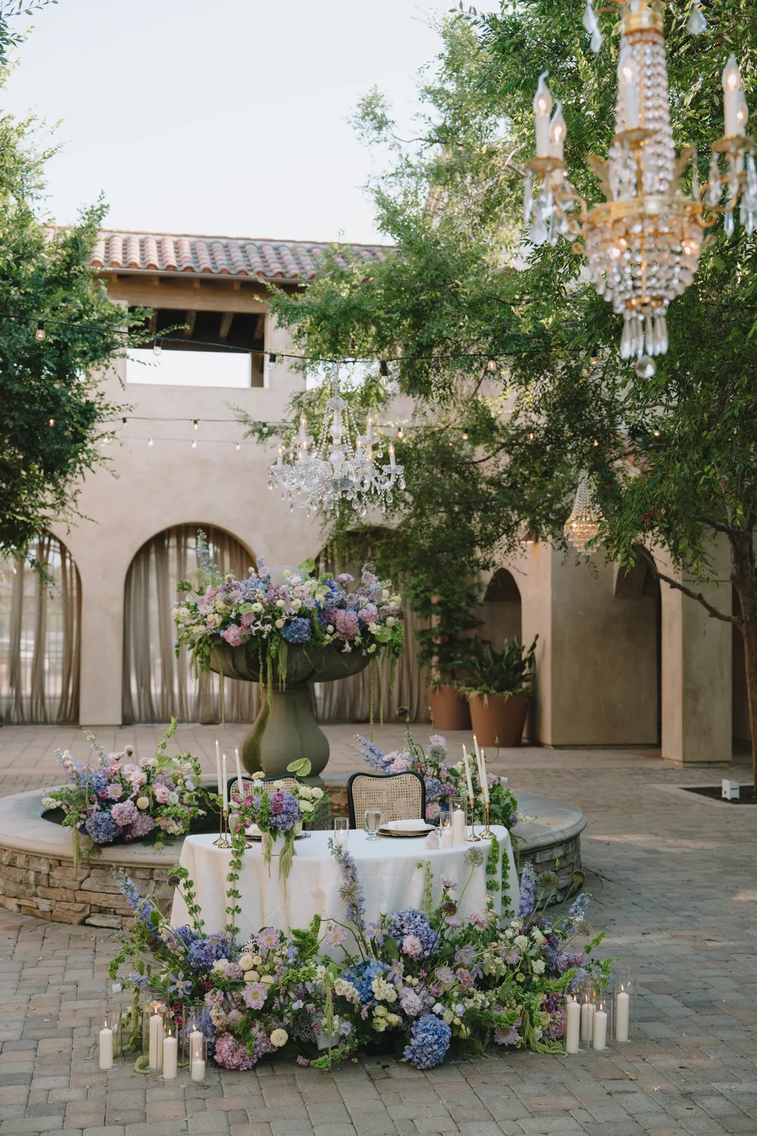 Floral sweetheart table and candles beside the Serra Plaza fountain.