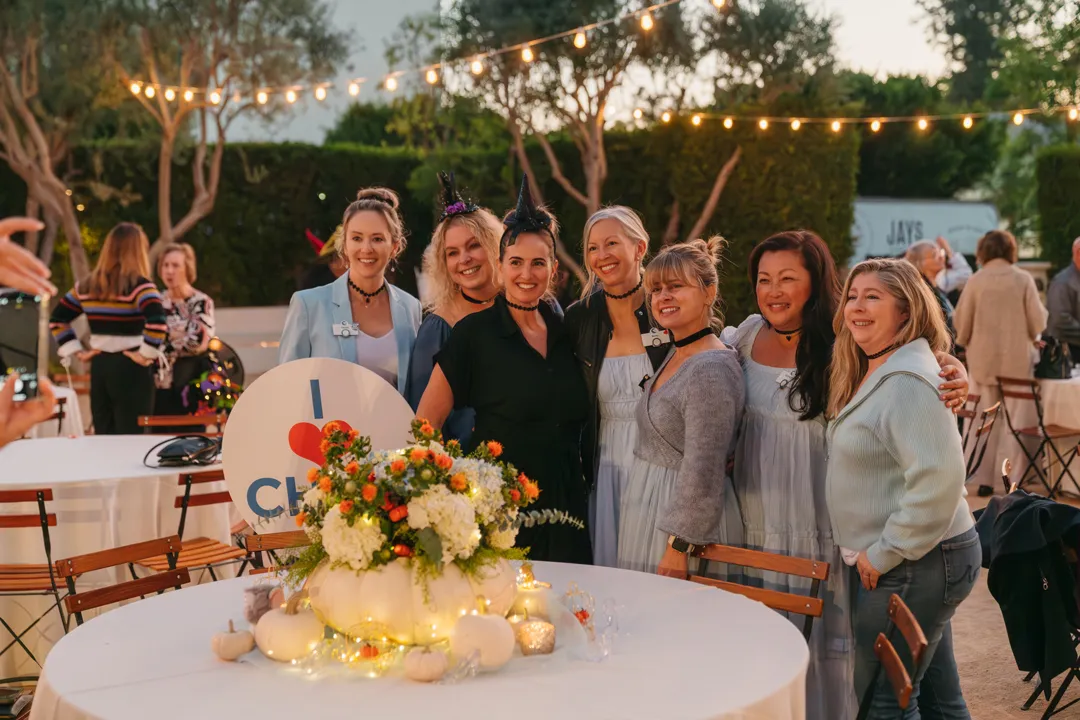 CHOC Guild Con group behind a floral centerpiece and an I Love CHOC sign.