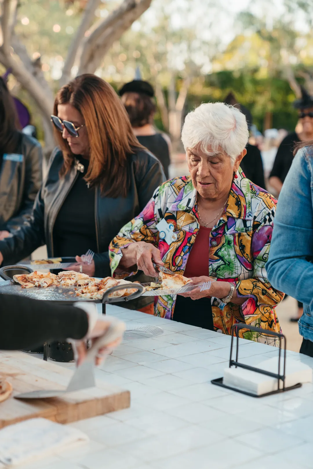CHOC Guild Con attendees receiving pizza from the outdoor kitchen.