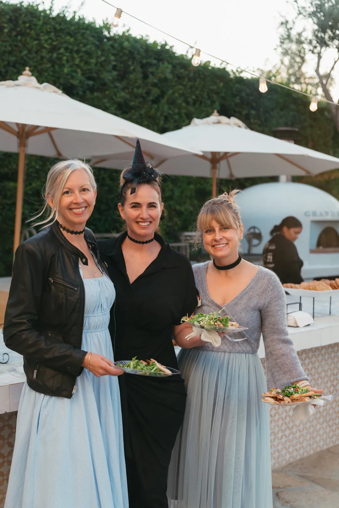 Three CHOC Guild Con guests posing beside Grand Gimeno's outdoor kitchen.