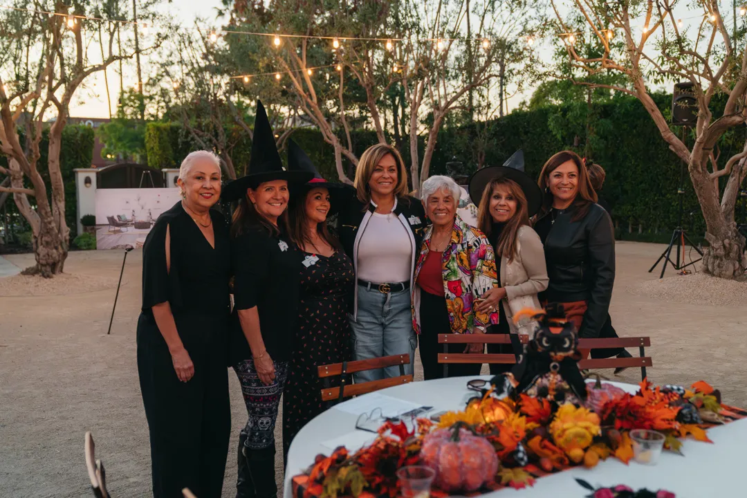 CHOC Guild Con attendees posing beside an autumn-themed centerpiece.