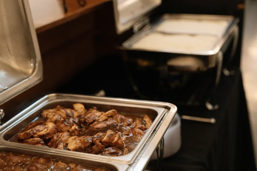 Warm buffet trays filled with sauced chicken pieces.