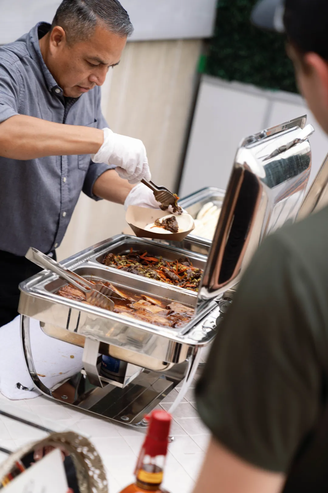 Server portioning food from a chafing dish.