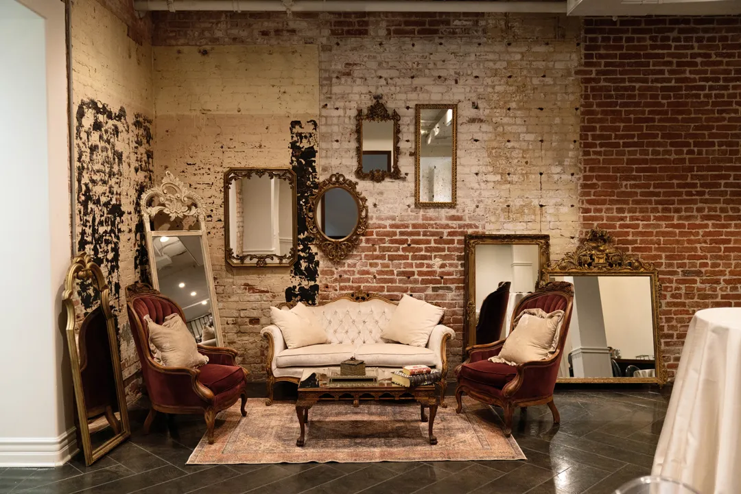 Vintage sofas and ornate mirrors against The Estate on Second's exposed brick wall.