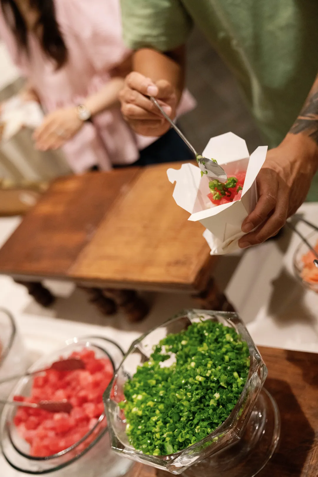 Guest adding green toppings at the Jay's Catering Poke Station.