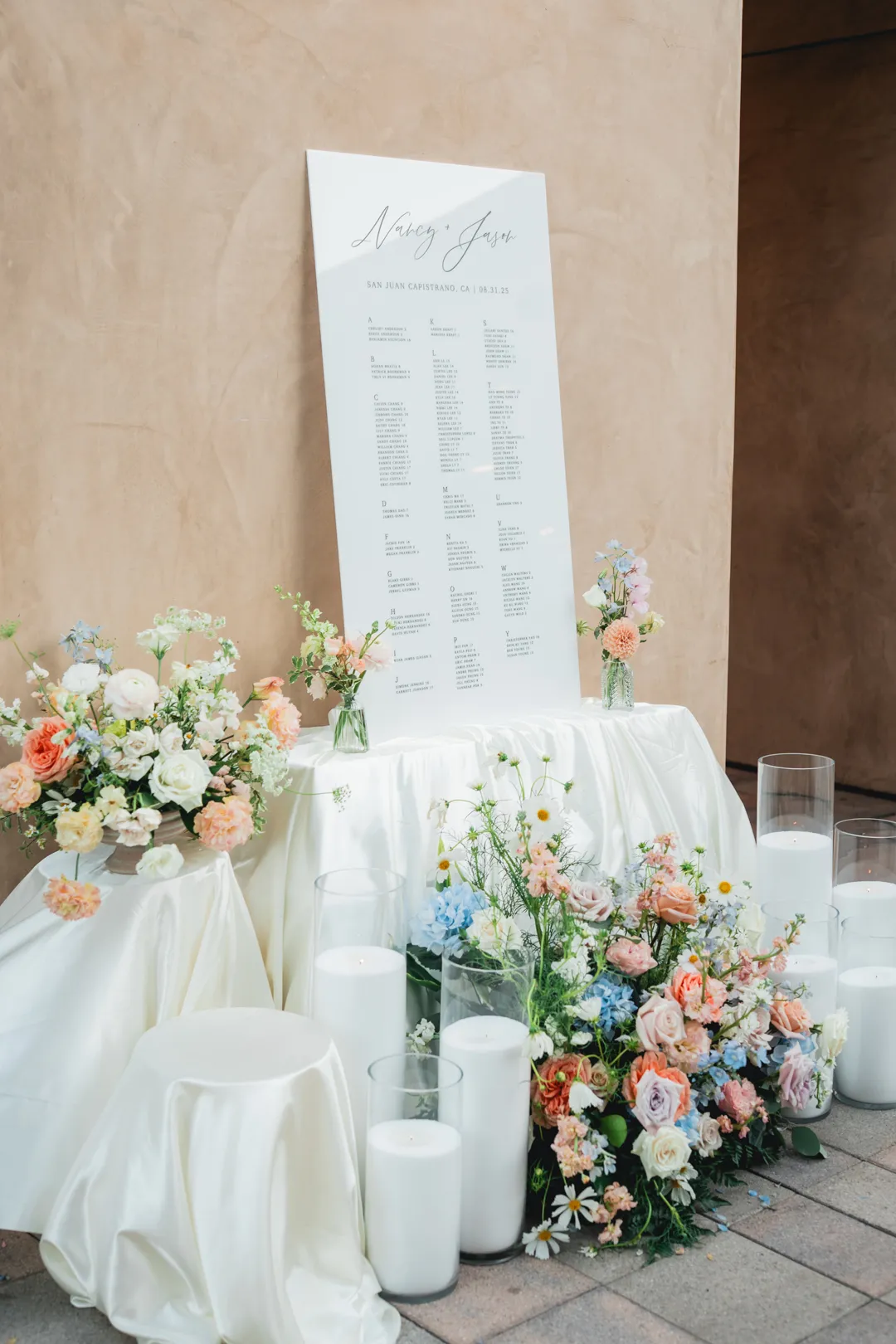 Wedding seating chart surrounded by pastel flowers and candles at Serra Plaza.