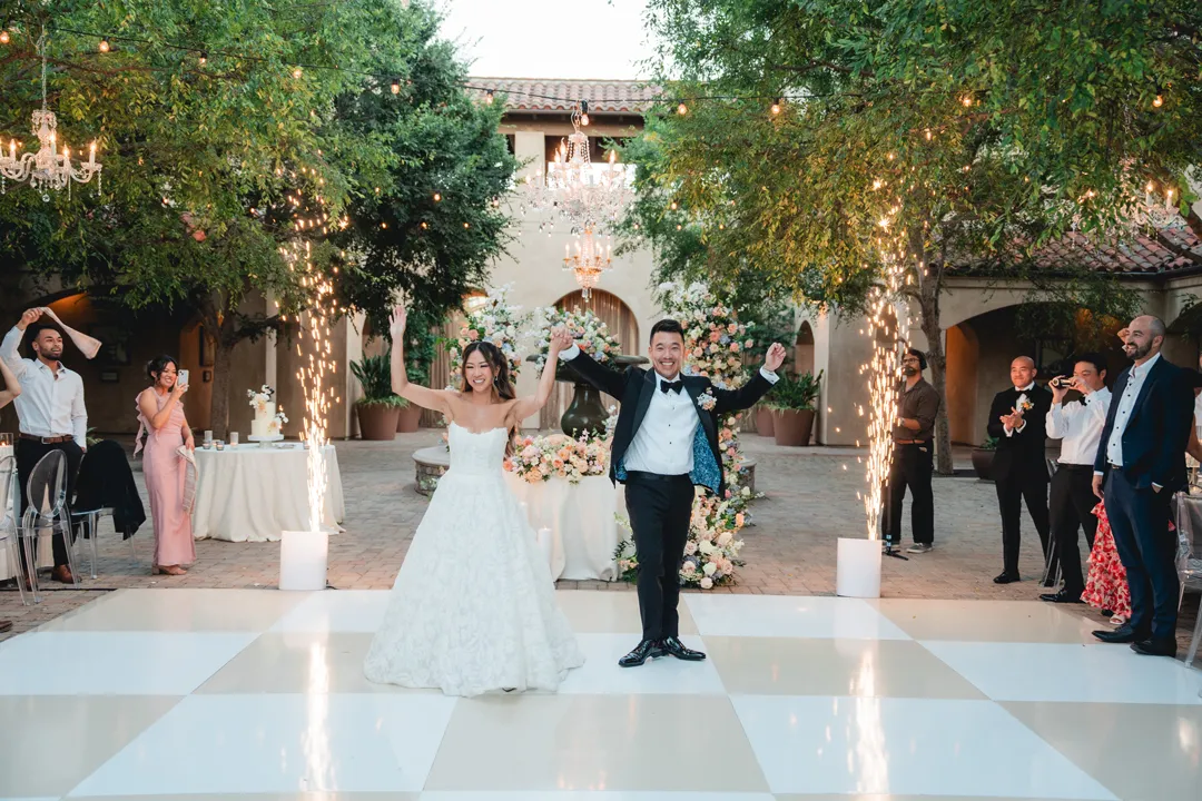 Newlyweds celebrating between spark fountains in the Serra Plaza courtyard.